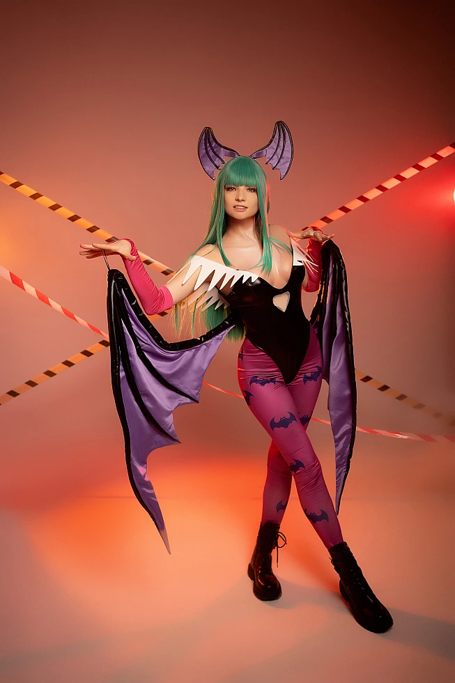 Morrigan Aensland cosplay grounded full-body stance, open wings, warm studio lighting, diagonal tape accents, glossy bodysuit