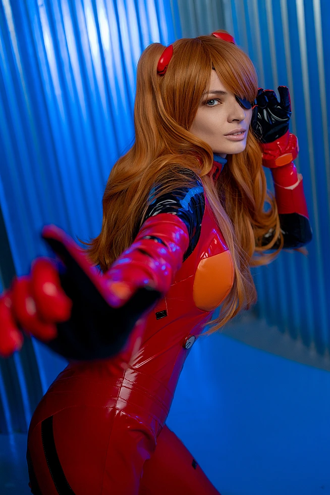 Dynamic Asuka Langley cosplay close-up with extended red gloved hand reaching toward camera, plugsuit with blue industrial backdrop reflections