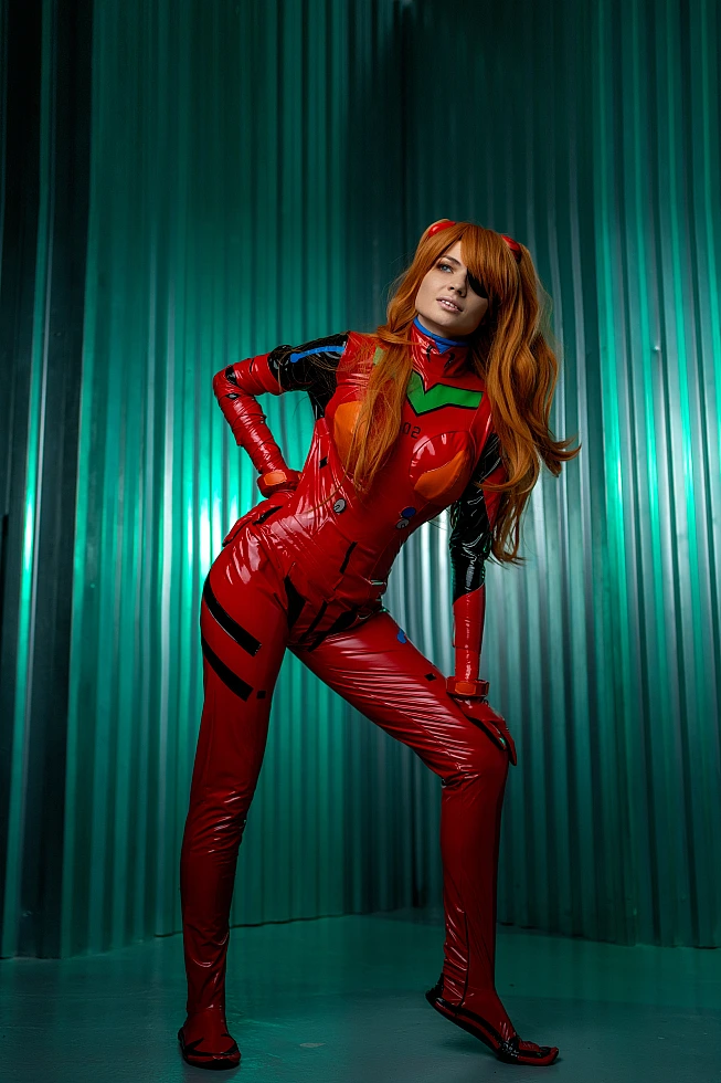Confident Asuka Langley cosplay leaning pose with hand on hip, glossy red plugsuit against green-lit metallic industrial backdrop, eyepatch visible