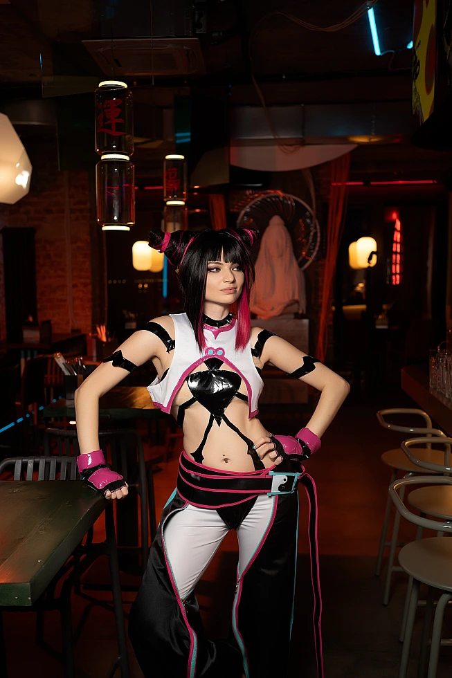 Juri Han cosplay standing centered in neon bar with strong symmetrical pose, hanging lights and warm ambient lighting