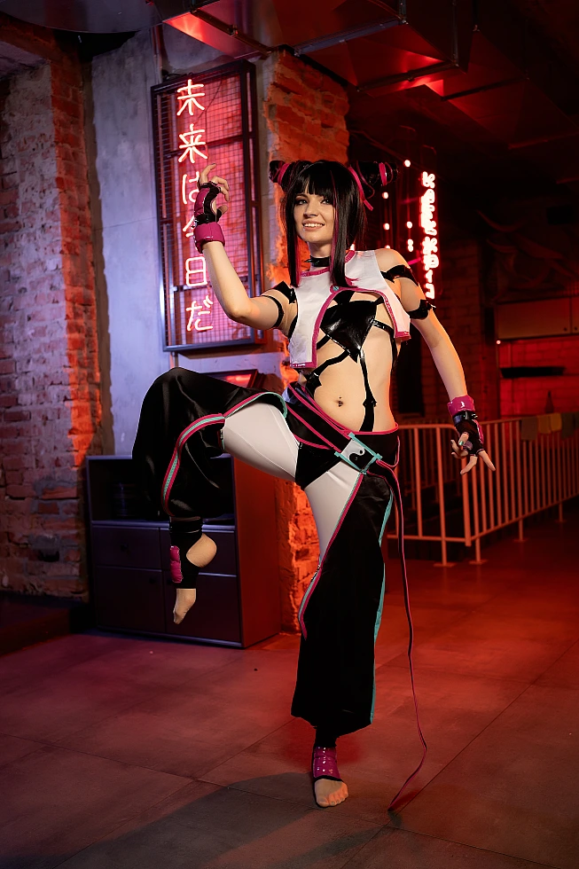Juri Han cosplay performing raised-leg kick pose under red neon signs with sharp hand gesture and glossy costume highlighting movement