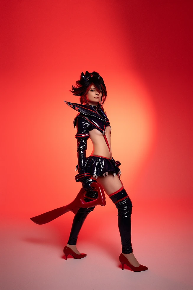 Ryuko Matoi cosplay holding scissor blade in crimson red studio lighting wearing glossy black Senketsu costume from Kill la Kill anime