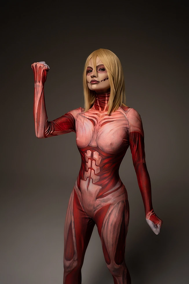 Female Titan cosplay power pose, Annie Leonhart raised fist, anatomical muscle bodysuit, dark background AOT cosplay