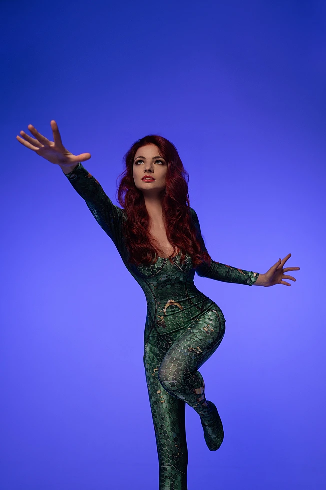Dynamic Mera cosplay reaching forward in balance pose wearing emerald scale bodysuit