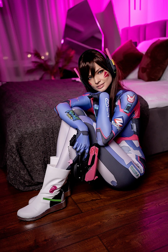 D.Va cosplay bedroom floor scene, soft pink neon ambience, Overwatch light gun prop, cinematic gaming cosplay photography