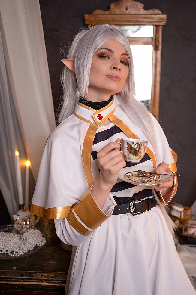 Frieren tea time cosplay - elf mage holding teacup in cozy fantasy setting from Sousou no Frieren