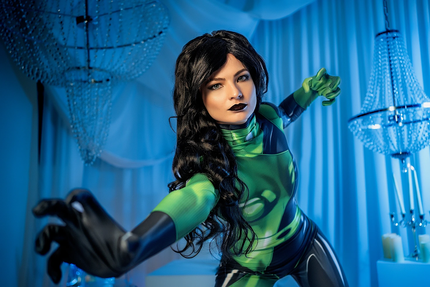Shego cosplay reaching toward camera, green-black suit, blue studio lighting