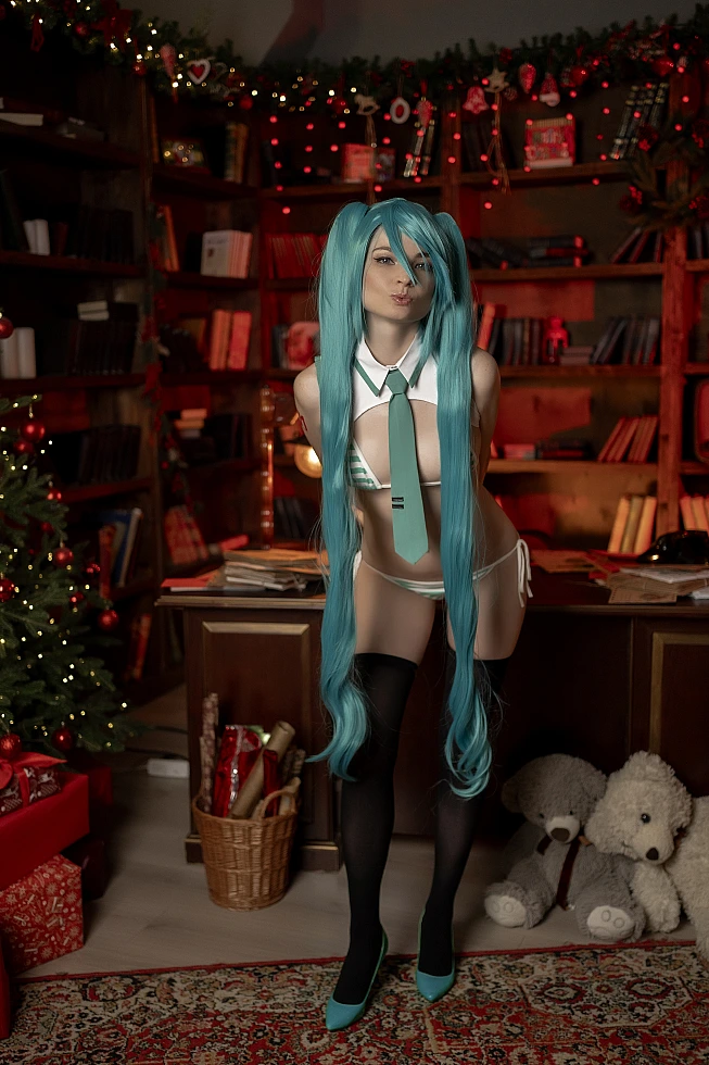 Cute Hatsune Miku holiday cosplay girl in playful forward lean pose with turquoise twin tails, striped boudoir costume, thigh-high stockings, cozy festive interior with Christmas lights