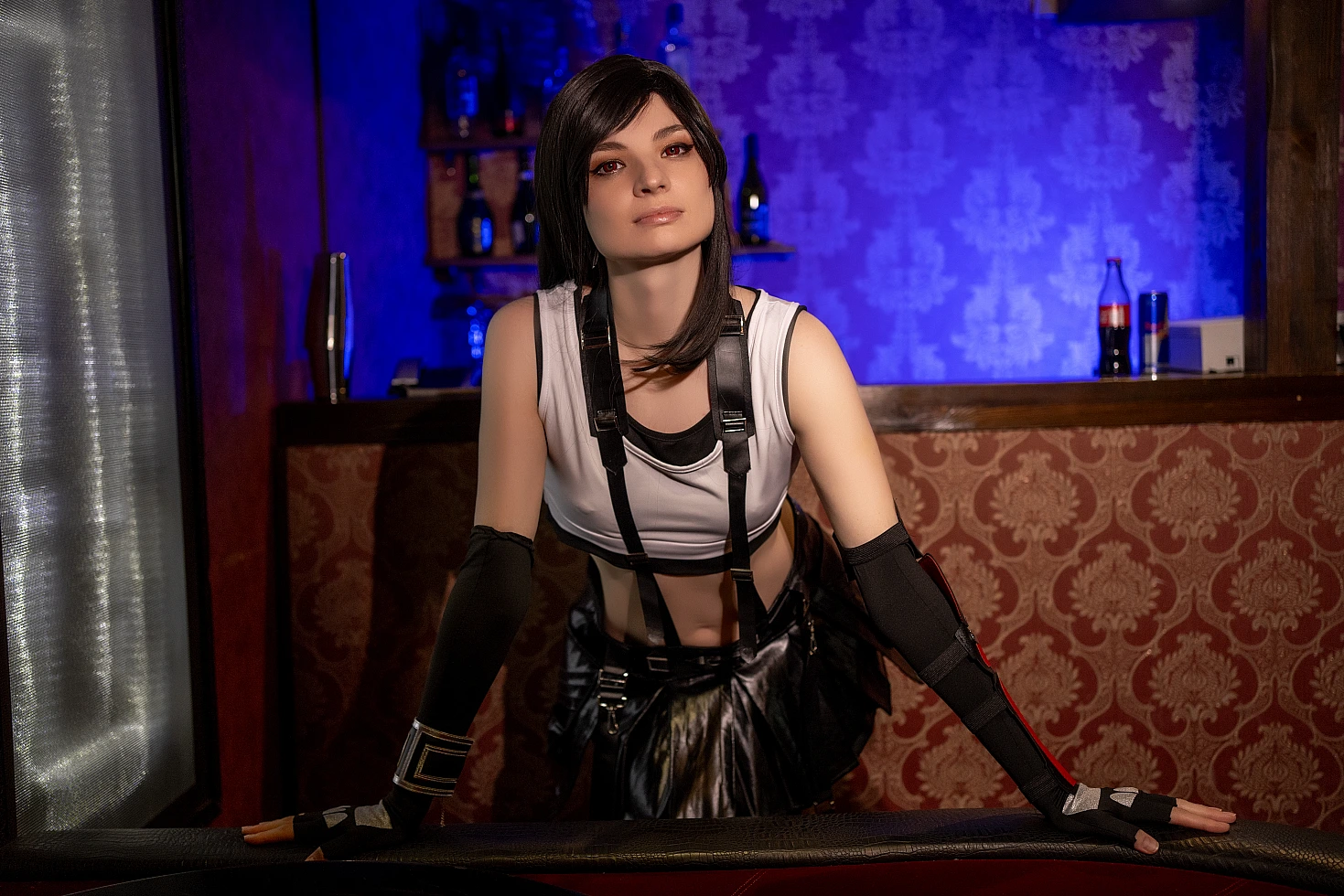 Tifa Lockhart bartender cosplay leaning on bar counter, direct confident gaze, FF7 costume with suspenders, toned arms, warm ambient bar lighting