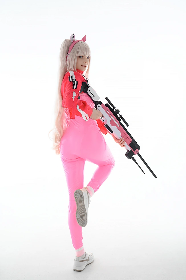 Alice cosplay from Goddess of Victory Nikke posing with a sniper rifle in a bright white studio background