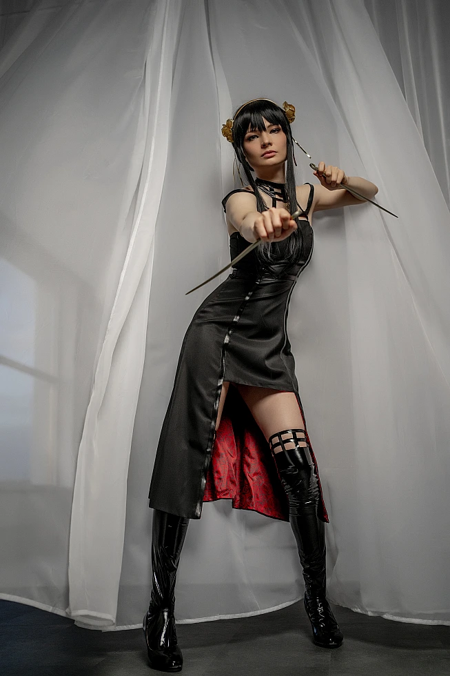 Yor Forger from Spy x Family lunges toward the camera between white curtains, a gold stiletto held out at arm's length.